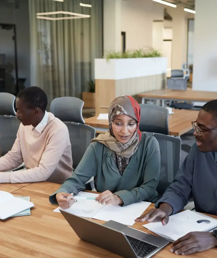 Trois personnes travaillent sur des documents autour d'une table de réunion